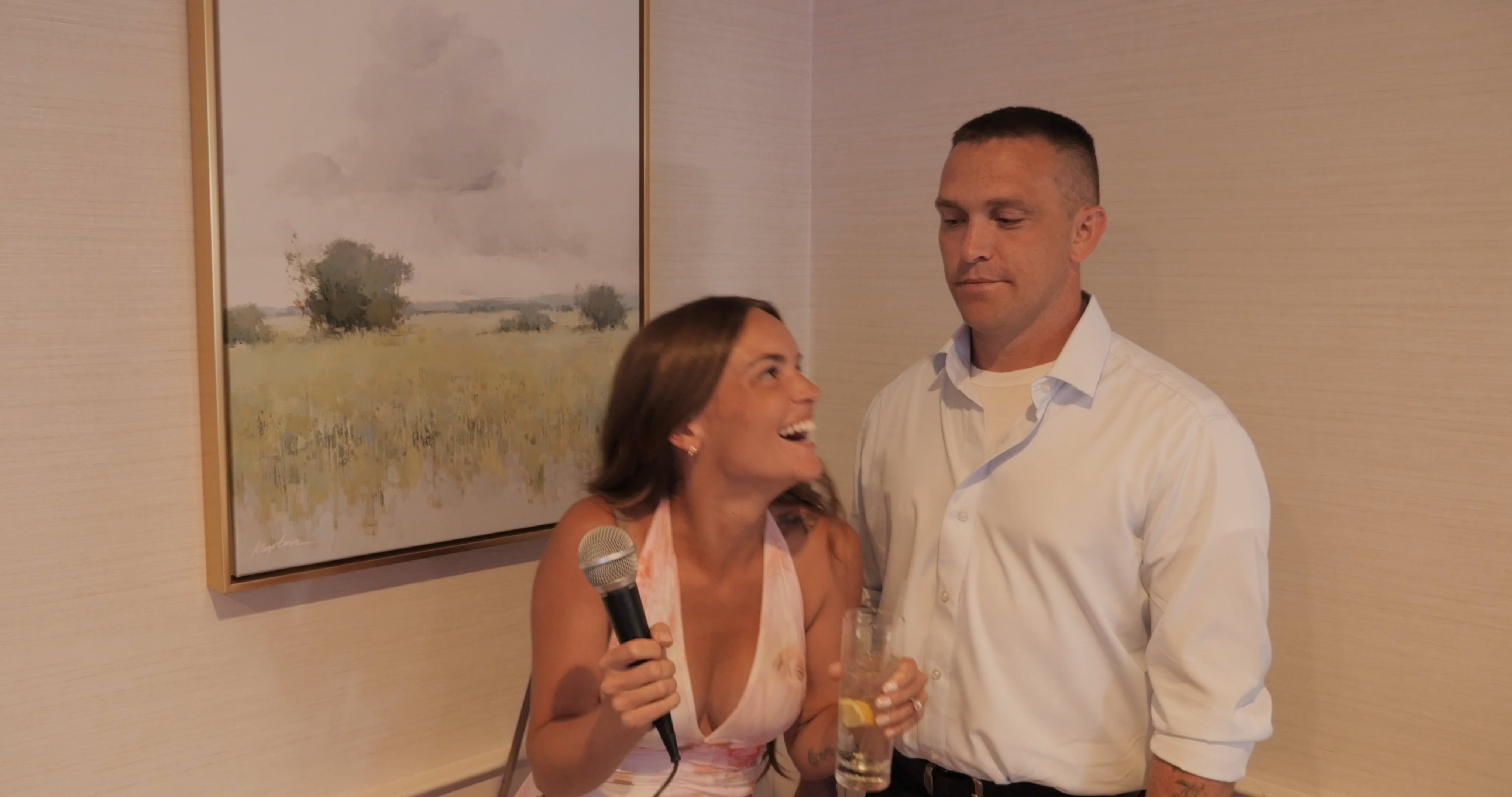 A wedding guest laughing with a microphone beside another guest in Michelle and Paige’s Confessional Corner